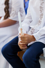 A Young Boy Holding a White Candle During a Religious Ceremony