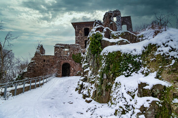 A castle with a snow covered roof and a steeple. The castle is surrounded by a snowy landscape....