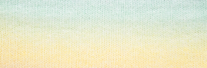 Light yellow green soft knitted fabric pattern background. Closeup. Wide banner. Top down view.