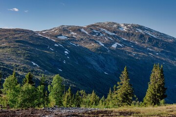 Beautiful landscape of snow-capped mountains under a clear blue sky with scattered clouds.