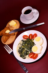 Healthy breakfast. Fresh boiled eggs with cherry tomatoes and spinach in cheese sauce. Coffee and buttered toast. Proper nutrition.