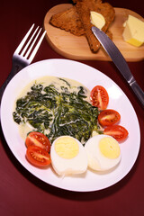 Healthy breakfast. Fresh boiled eggs with cherry tomatoes and spinach in cheese sauce. Coffee and buttered toast. Proper nutrition.