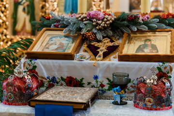 Religious Altar with Icons, Cross, and Ornate Crowns Surrounded by Decorative Floral Arrangements