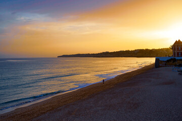 Naklejka premium Golden Sunset over tranquil Beach with calm Waves and expansive horizon, casting warm light over the Sea and Sand. Copy Space 