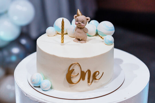 Adorable First Birthday Cake with Bear Topper and Decorative Swirls