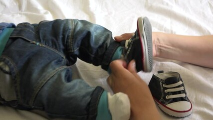 Mother hands puts baby shoes on