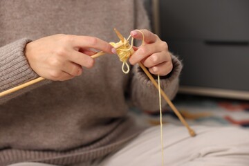 Woman knitting with needles at home, closeup