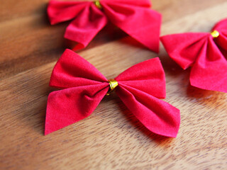 Festive velvet bow for Christmas and new year in red with a gold ribbon on a woody background. Decor and decorative decorations