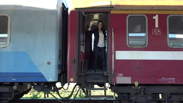 Young woman waving hand in train at departure