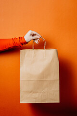 Eco-friendly paper bag for takeaway or delivery with a minimalistic design on orange background
