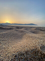 Sun rising behind mountains, view from the beach