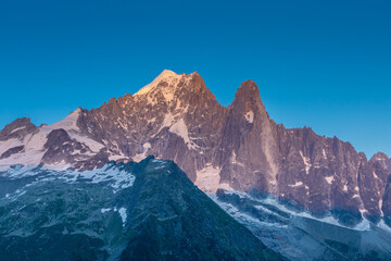 The Petit Dru mountain summit displays rugged peaks and rocky formations against clear sky. Rocky...