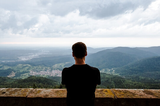 Mann schaut von einem Turm &uuml;ber Wald und D&ouml;rfer bei tr&uuml;ben Wetter
