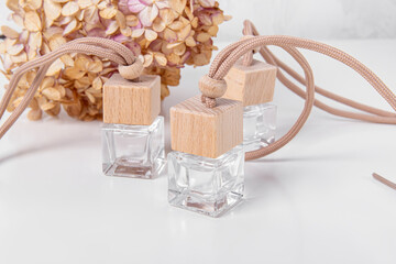 Three car air fresheners with floral aroma. Square bottles of car perfume and hydrangea