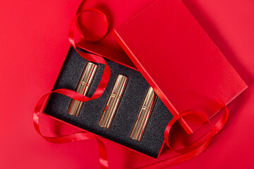 Red perfume gift box with red ribbon on red background