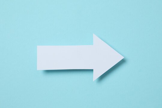 Paper arrow on gray background, top view