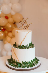 Elegant White Wedding Cake with Gold Accents and Greenery Decoration