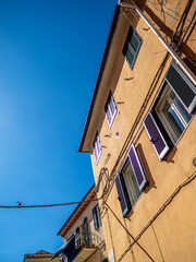 Gelbe Hausfassade mit Fensterläden auf Elba, Italien: Charmante Architektur in Froschperspektive