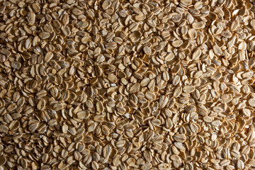 Uncooked Oat Flakes background - Top View, Flat Lay. Scattered Dry and Raw Oat Flakes. Healthy Breakfast and Diet Eating Ingredients