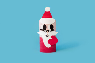 Christmas toy from toilet tube roll, paper toy santa claus on light blue background. Holiday easy DIY for kids, decoration idea for winter season home xmas party. Children's crafts