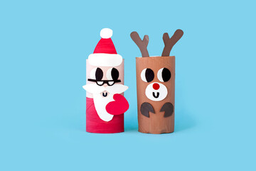 Christmas toy from toilet tube roll, paper toy santa claus, snowman, reindeer, tree rabbit on blue background. Holiday easy kids DIY, decoration idea for winter season, home party. Children's crafts