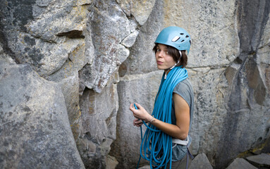 A young girl is mountaineering, checking equipment and straightening the rope before going in a bunch to the top of the mountain.