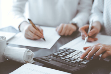 Two accountants use a calculator and laptop computer for counting taxes or revenue balance. Business, audit, and taxes concepts