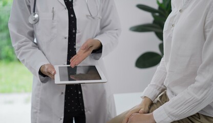 Doctor and a patient. The female physician is pointing into tablet computer besides a young woman during a consultation in the clinic, view above. Medicine concept