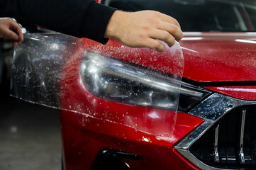 The process of applying protective vinyl film to car headlights in detailing. 