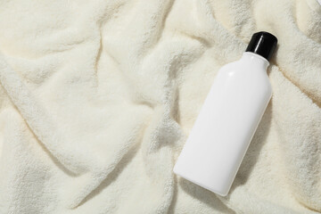 Shampoo in bottle on soft towel, top view. Space for text