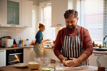 Smiling man kneading dough while baking in kitchen.