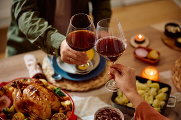 Close up of couple toasting during Thanksgiving dinner at dining table.