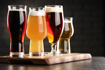 Glasses with different types of beer on wooden table in bar, closeup