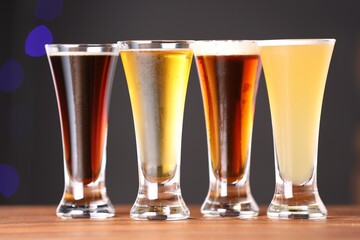 Glasses with different types of beer on wooden table, closeup