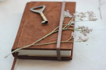 Vintage diary with old key and herbarium. Brown suede notebook. Vintage scene. Handmade notebook close up. Personal diary