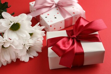 Gift boxes with bows and flowers on red background