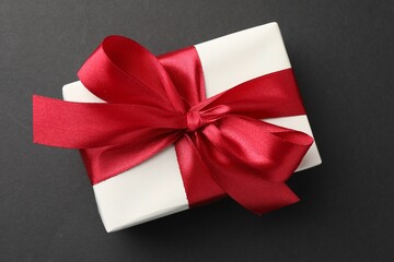 Gift box with red bow on black background, top view