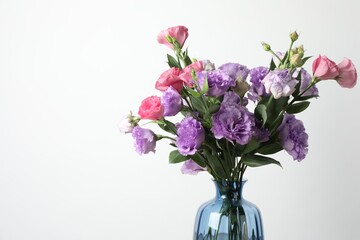 Vase with beautiful eustoma flowers on light background, space for text