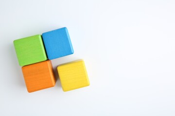 Many wooden colorful cubes on white background, top view. Space for text
