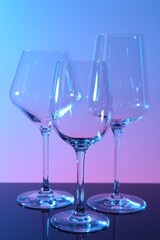 Empty glasses on table against color background