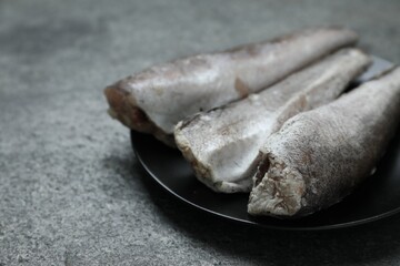 Frozen hake fishes on grey table, closeup