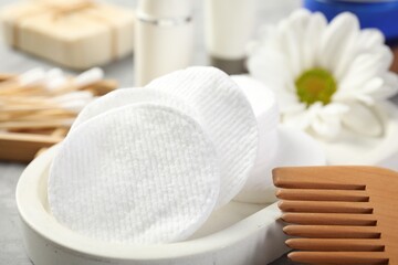 Clean cotton pads and comb on grey table, closeup