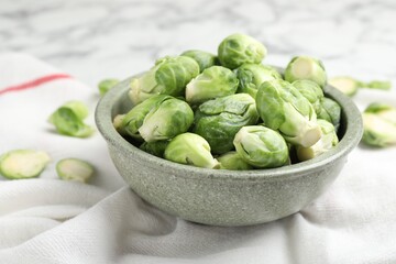 Fresh Brussels sprouts in bowl on white table, closeup