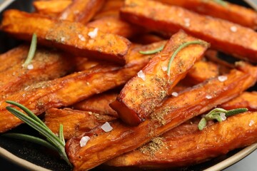 Delicious sweet potato fries with spices in bowl, closeup