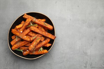 Delicious sweet potato fries with spices in bowl on grey table, top view. Space for text