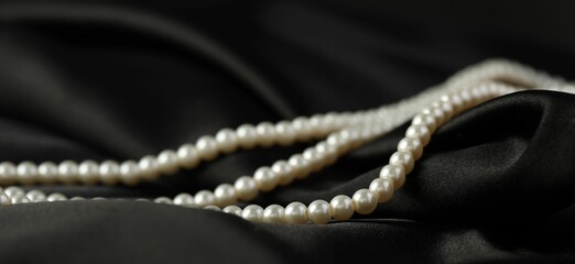 Beautiful pearl necklace on black silk, closeup
