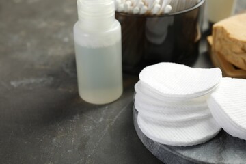 Many cotton pads and other toiletries on grey textured table, closeup