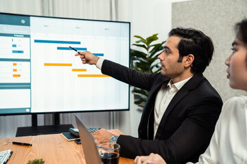 Project manager planning schedules for business task at meeting room, Gantt chart software show on TV screen. Multi ethnic diversity business people and modern business project management. Habiliment