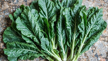 Freshly cut collard greens on stone surface showcasing broad dark green leaves with visible veins