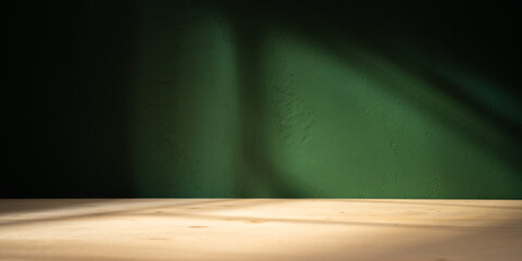 Empty table on green texture wall background. Composition with leaves shadows on the wall and light reflections. Mock up for presentation, branding products, cosmetics food or jewelry.	
